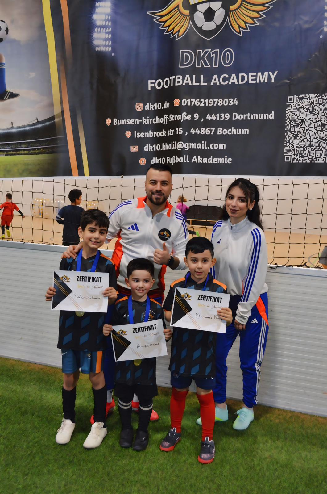 Ein Mann und eine Frau lächeln glücklich mit drei Jungen, die Zertifikate halten